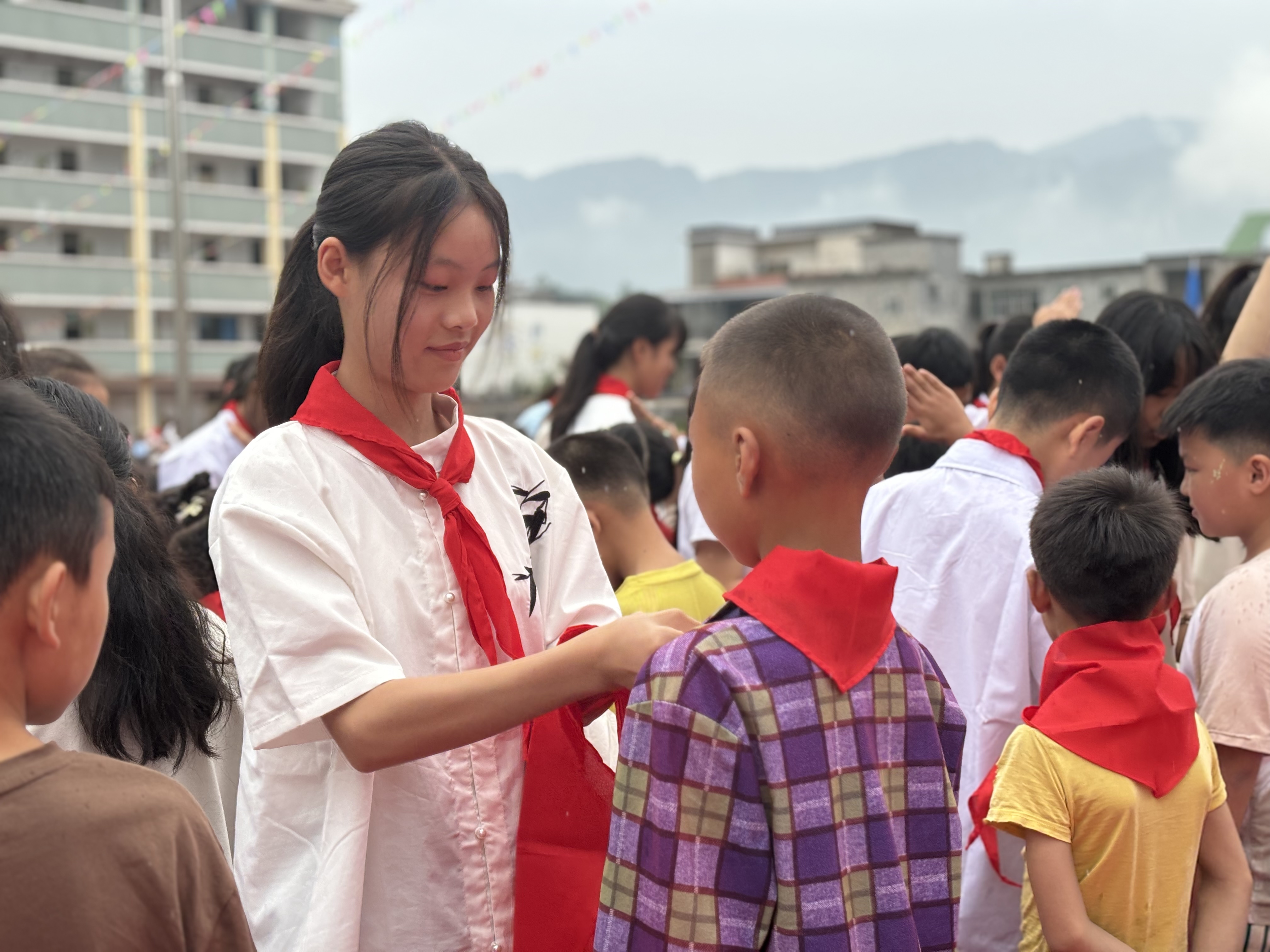 老队员为新队员佩戴红领巾